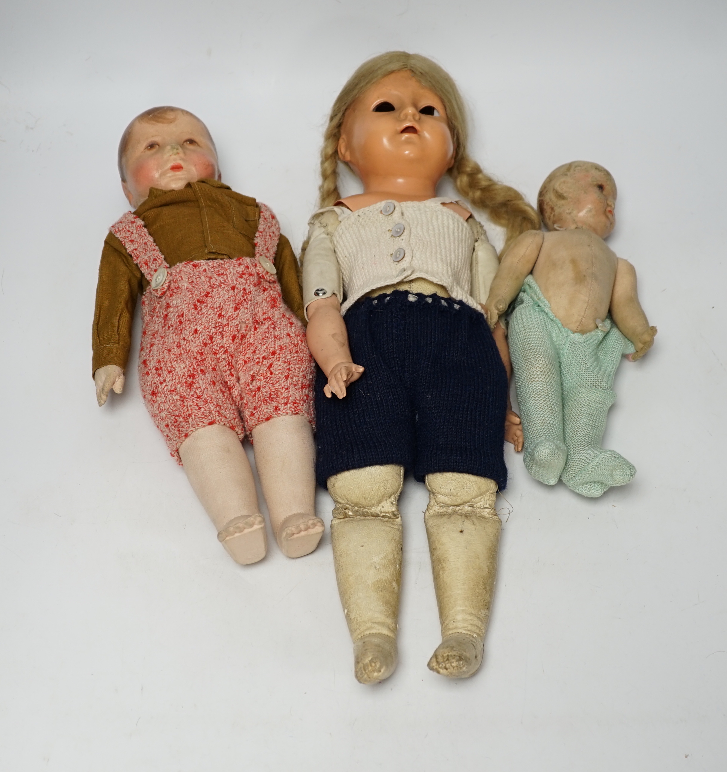 Three dolls including one by Kathe Kruse, original shirt, height 36cm, nose rubbed, one cloth doll, one celluloid with turtle mark eyes in head, height 46cm, original wig